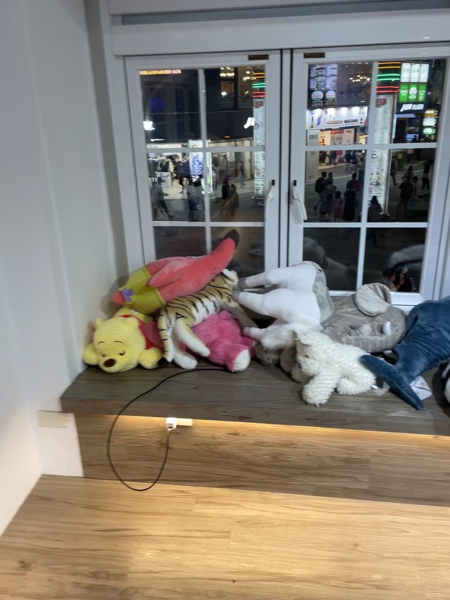 Joy&Ray 西門店二樓窗台上的絨毛娃娃堆，混放三麗鷗、迪士尼與各式布偶，窗外是西門町夜間街景