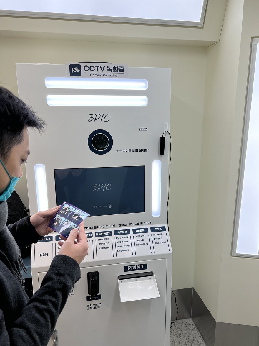 3PIC 的機台操作面板，顧客正手持成品站在機台前，機台上方為相機模組與 CCTV 녹화중標示