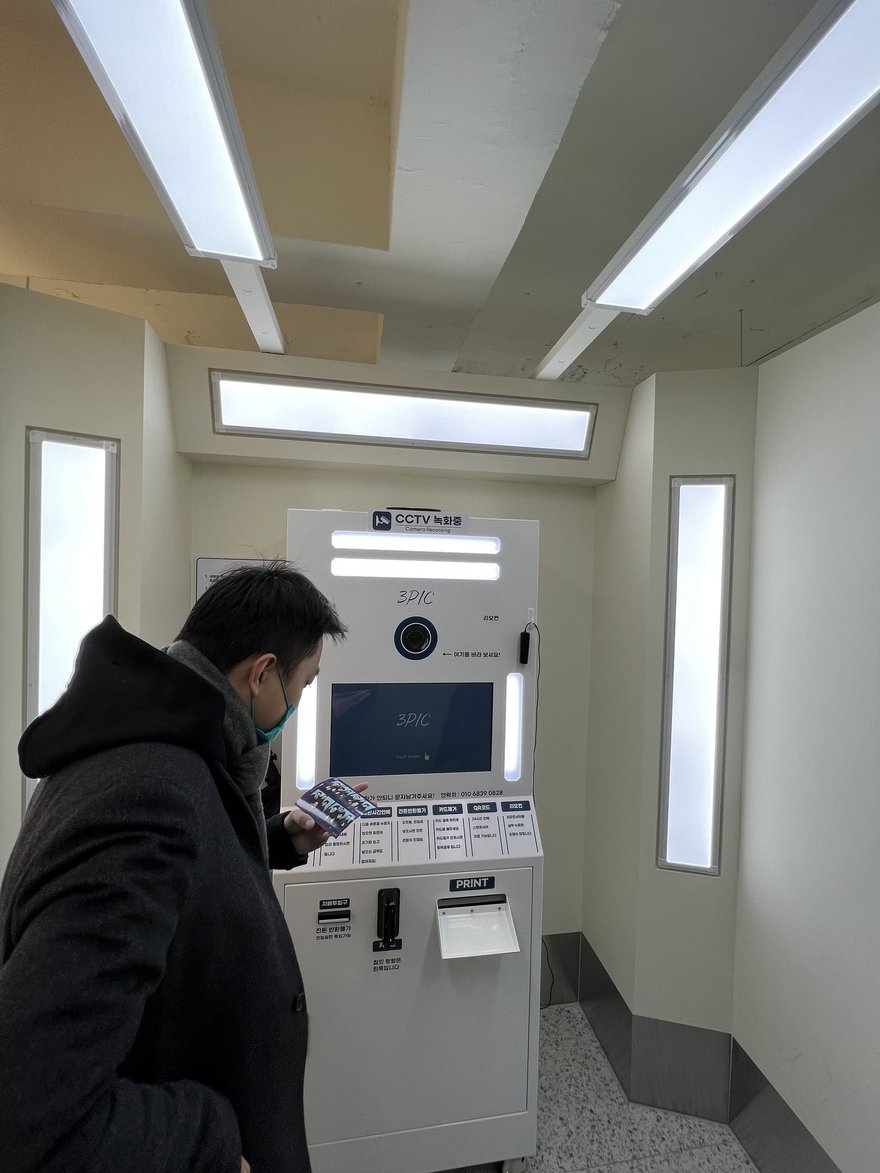 3PIC 店內的機台全景，白色機身、觸控螢幕與側邊燈條，地面為淺色磨石子