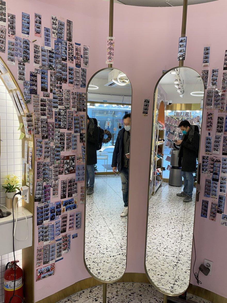 인생네컷店內的雙面立鏡與樣張牆，鏡面兩側同樣貼滿顧客照片