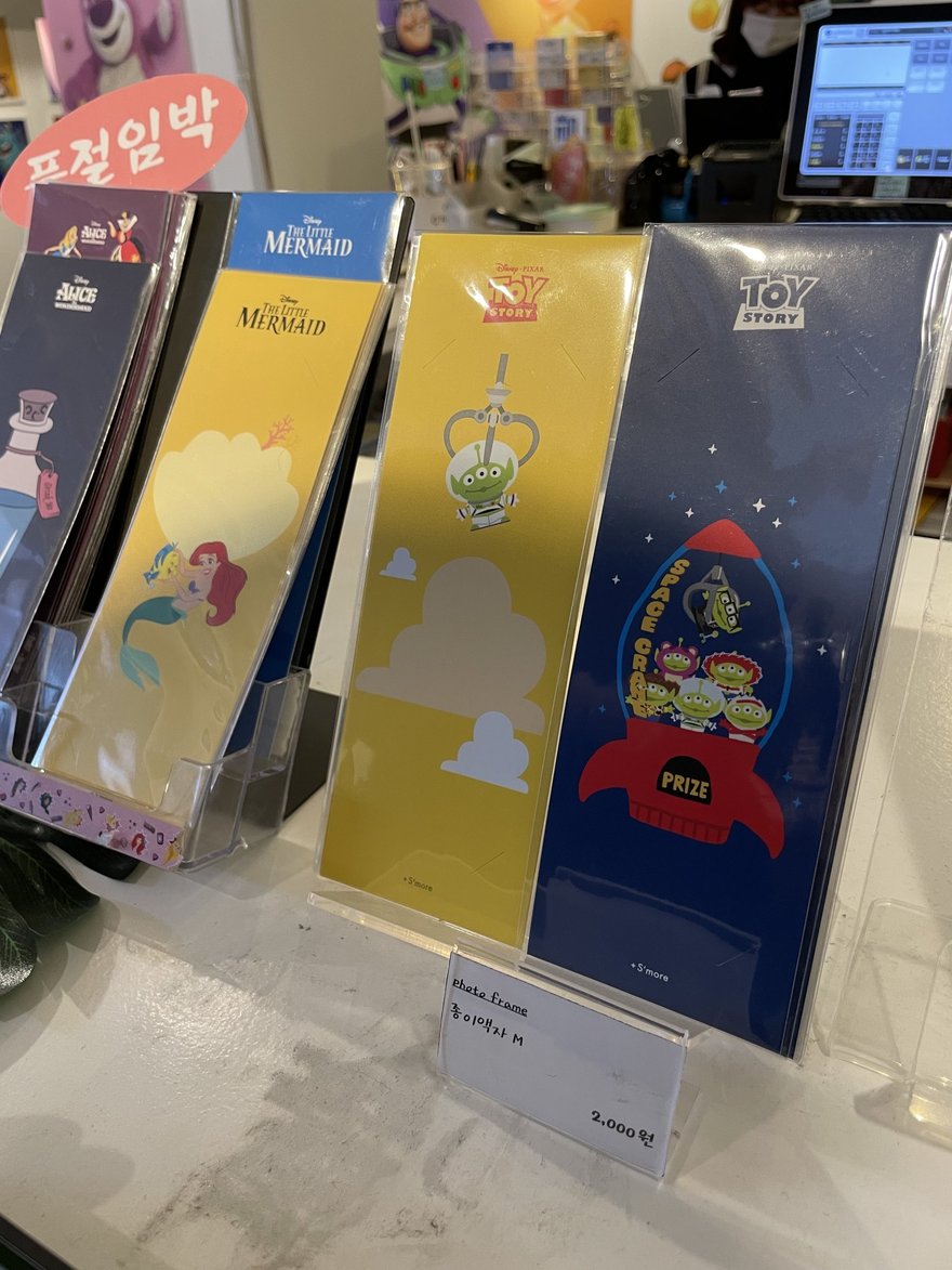 人生四格門市的相框商品陳列架，直立擺著多款印有卡通角色的彩色相框，架上有價格標示。