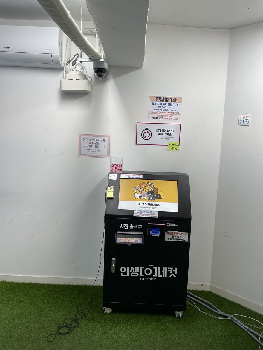 인생네컷複合店內的自助機台，機身印인생네컷品牌名，地面為人工草皮
