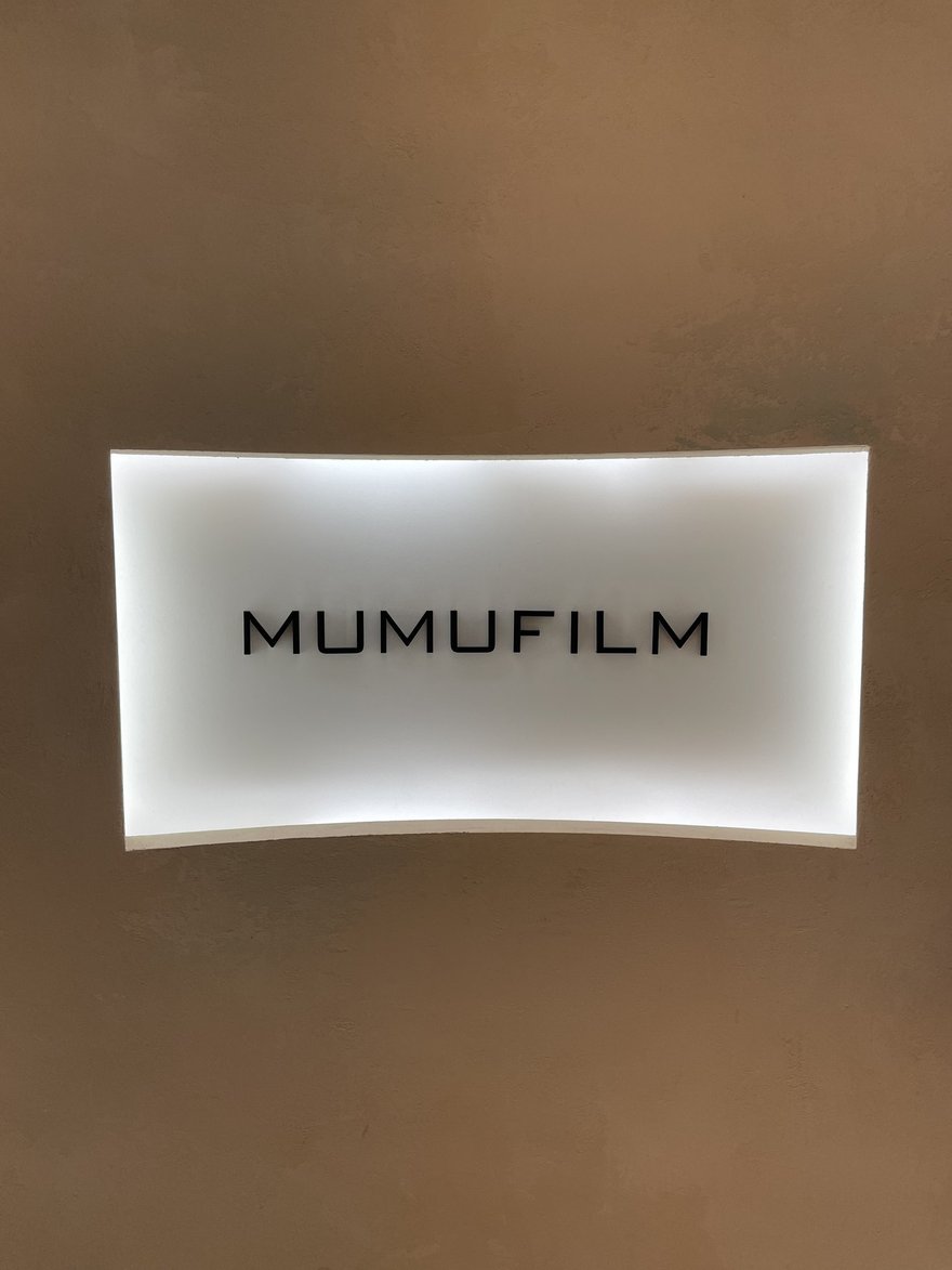 MUMUFILM 店內的品牌燈箱招牌，米色牆面上為白底黑字的 MUMUFILM