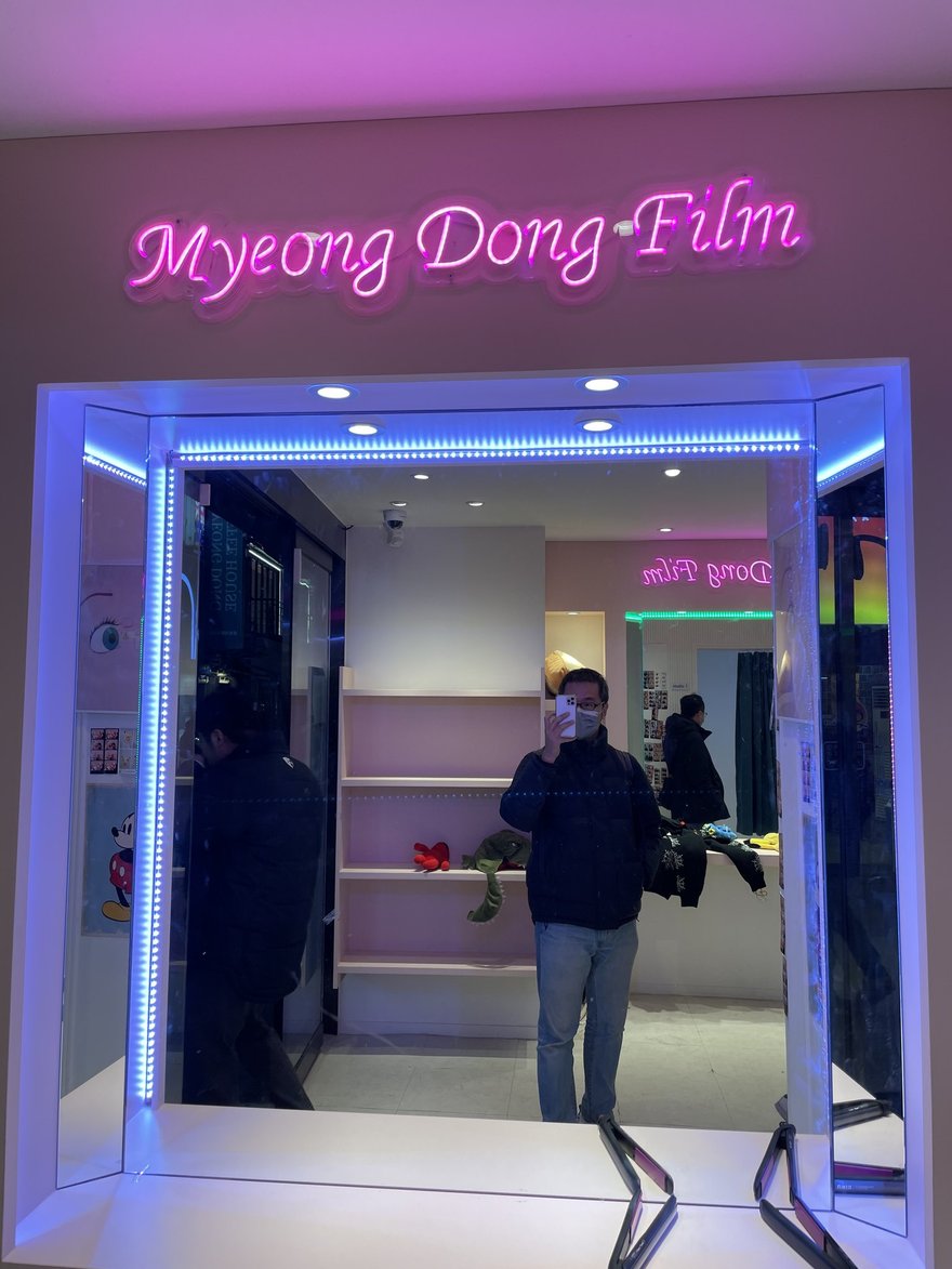 Myeong Dong Film 的店面入口，藍色 LED 燈框圍住整個門框，室內為粉色調空間