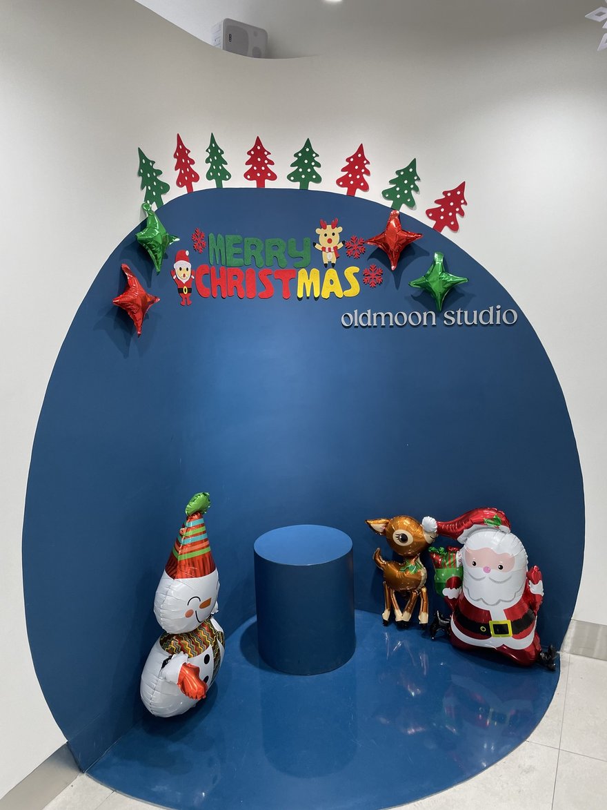 Oldmoon Self Studio 棚內的深藍色圓形拍攝背板，前方擺放聖誕老人與雪人裝飾，牆上印 oldmoon.studio