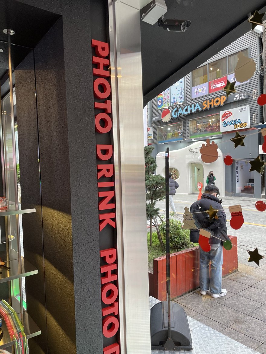 PHOTO DRINK 的門市外觀，黑色立面上為 PHOTO DRINK 直式招牌與紅色霓虹字