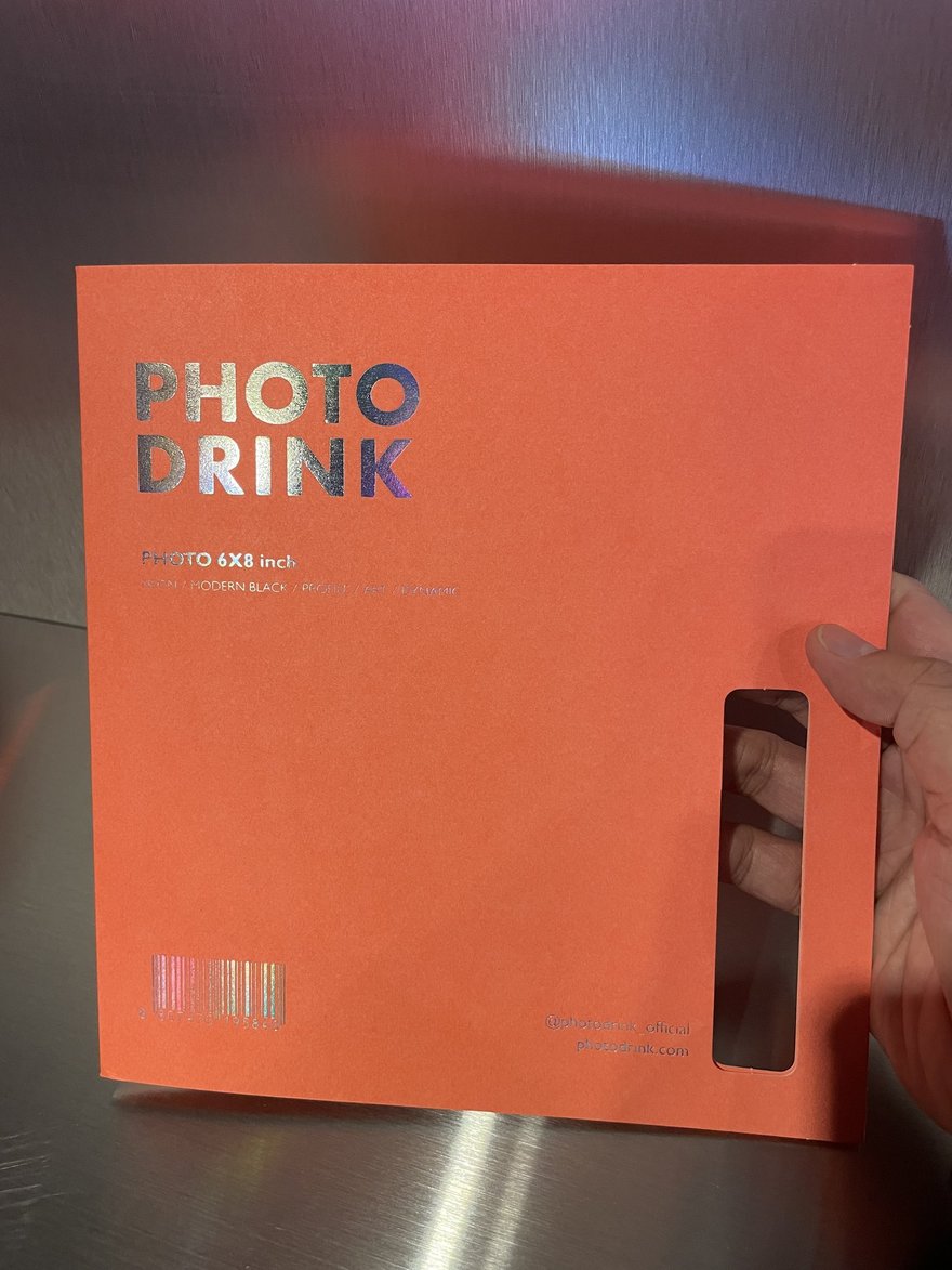 PHOTO DRINK 相冊的手持紀錄照，橘色封面與品牌名同框