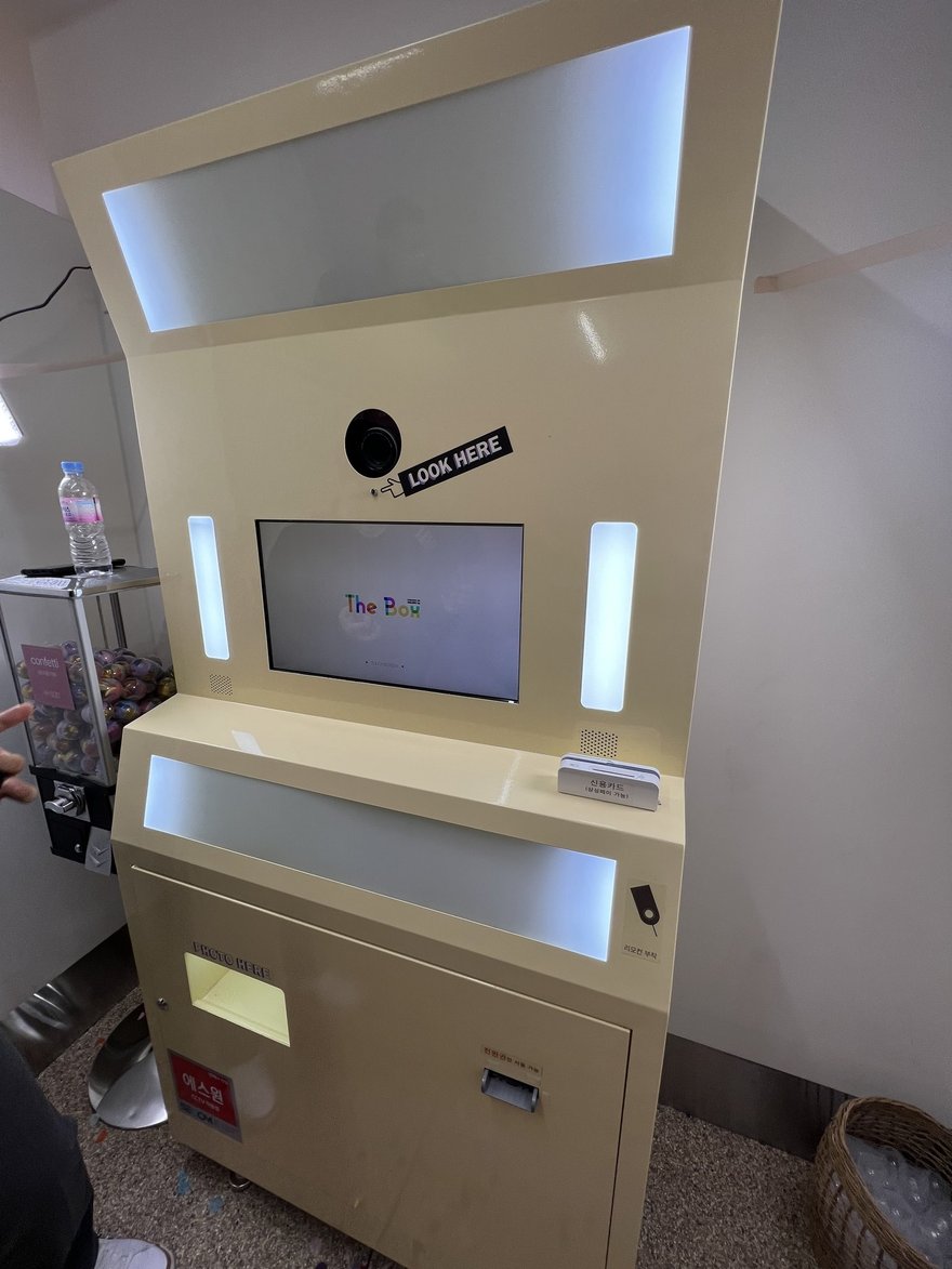 Photo in the Box 的另一台機器，機身白色、上方為 LOOK HERE 指示牌與相機