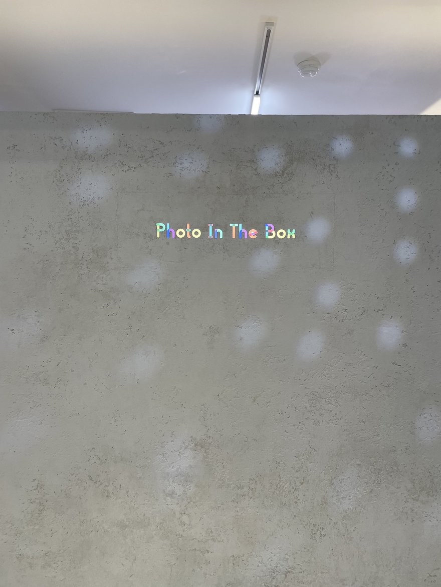 Photo in the Box 店內的白色牆面，牆上以燈光投出 Photo In The Box 字樣