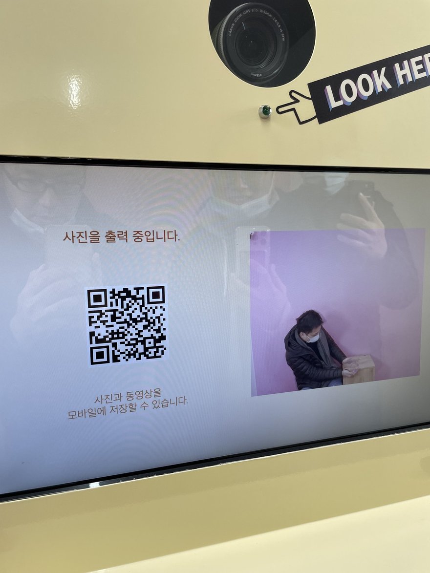 Photo in the Box 另一台機器的出片畫面，同樣顯示 QR code 與사진을 출력 중입니다字樣