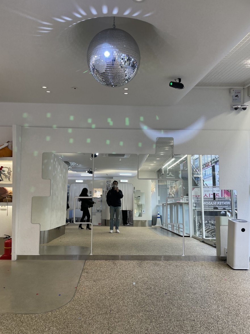 Photo in the Box 店內天花板懸掛的鏡球與白色走道，兩側為拍攝棚