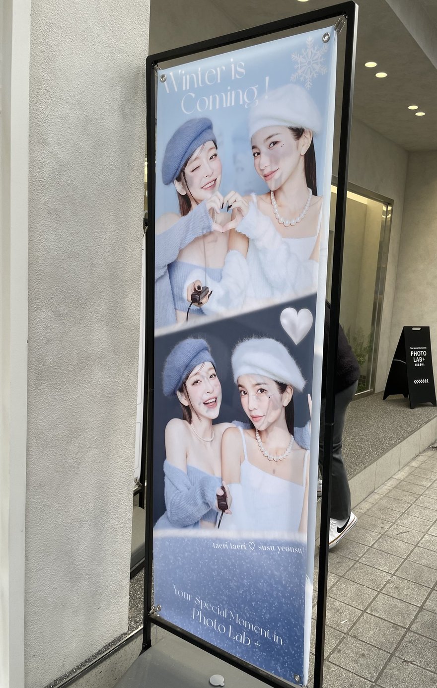 PHOTO LAB+ 門口的模特兒燈箱，兩位模特兒以雙手比心的樣張構成主視覺