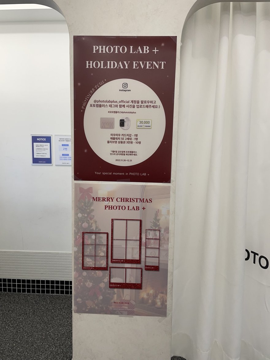 PHOTO LAB+ 店內的 HOLIDAY EVENT 與 MERRY CHRISTMAS 活動海報，紅色版面搭配白色布簾