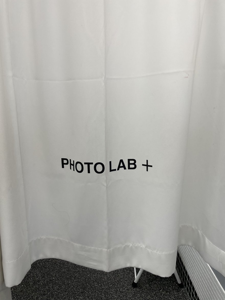 PHOTO LAB+ 的白色布簾更衣間，布簾上印 PHOTO LAB + 字樣