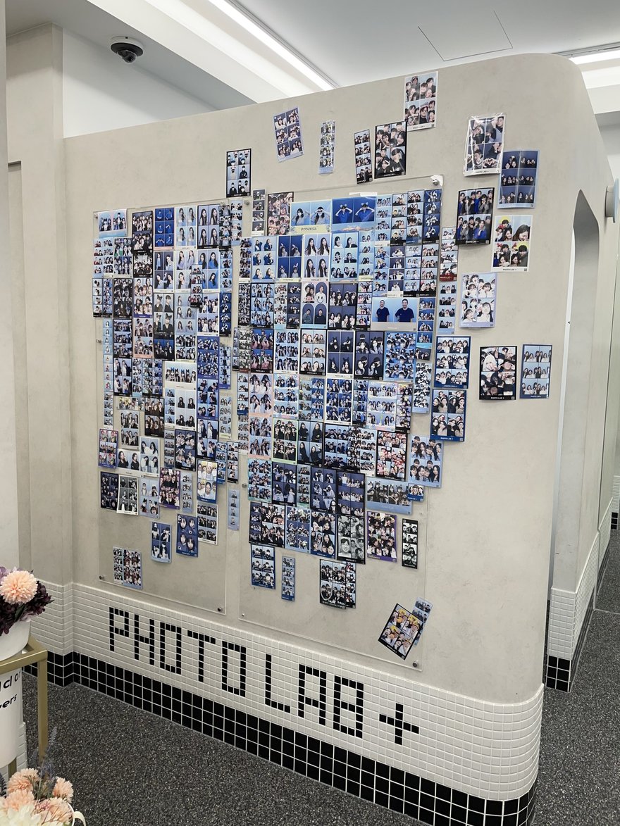 PHOTO LAB+ 店內的大面樣張牆與品牌字樣，牆下方印 PHOTO LAB +