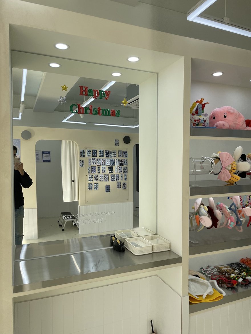 PHOTO LAB+ 店內的鏡面與道具層架，可見聖誕裝飾與絨毛玩偶
