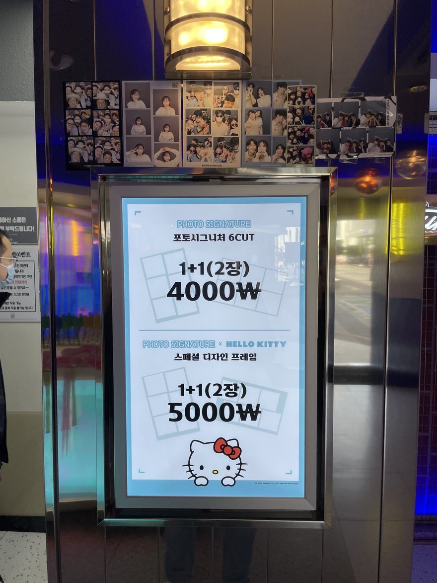 Photo Signature 地下街門市的價目牌，藍底燈箱標示 1+1（2장）4000W 與 5000W
