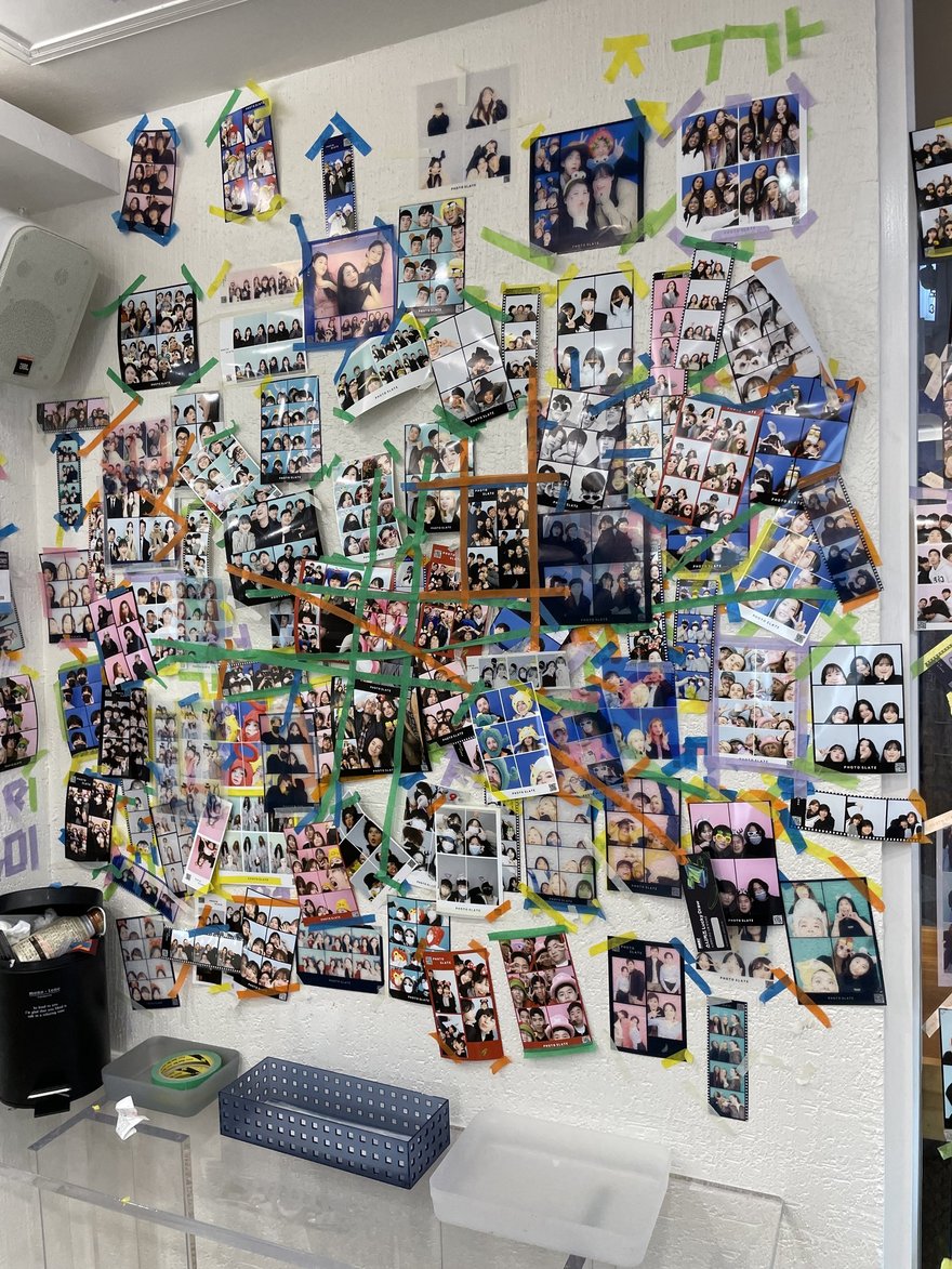 Photo Slate 店內的樣張牆，白色牆面上以彩色膠帶貼滿顧客留下的黑白與彩色四格照片