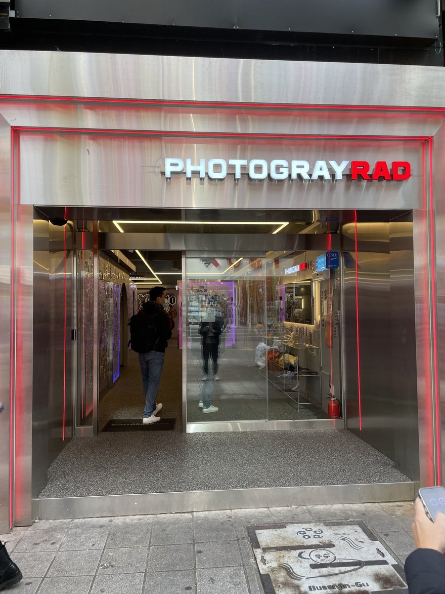 Photogray RAD 店內入口的走道，兩側牆面貼滿樣張，盡頭為拍攝棚入口