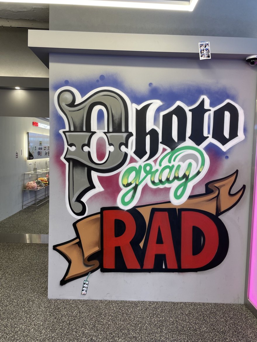 Photogray RAD 店內另一面塗鴉牆，同樣以街頭噴漆字體寫出品牌名，牆面兩側貼滿顧客留下的樣張