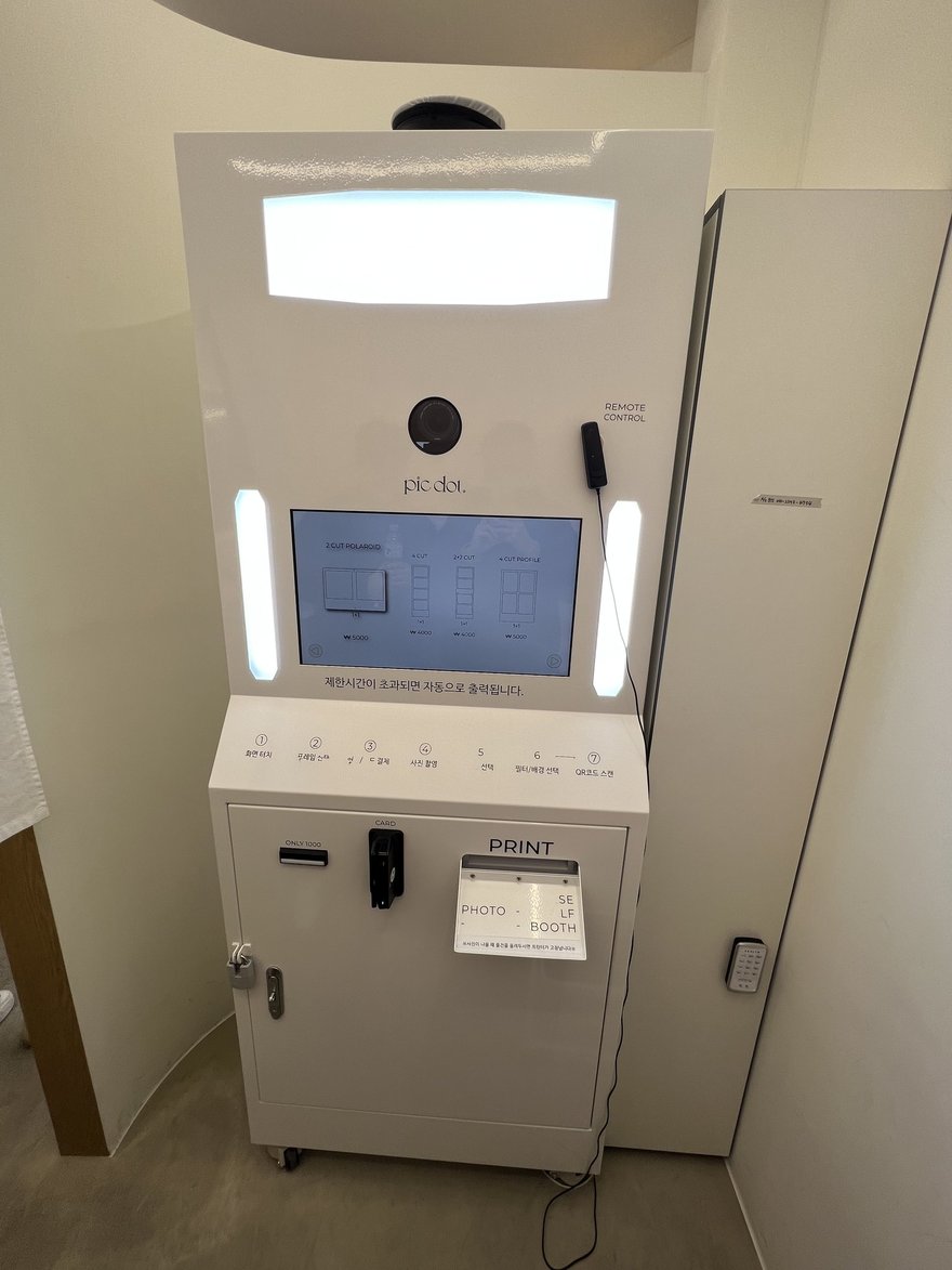 pic dot 的白色直立式機台，上方為柔光燈箱與相機模組，中央為觸控螢幕，下方為操作按鍵與出片口