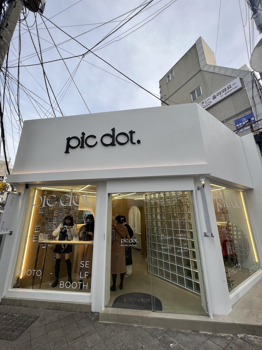 pic dot 釜山西面店的店面外觀，白色雨遮下方為玻璃磚立面與玻璃門，招牌以小寫襯線字寫 pic dot