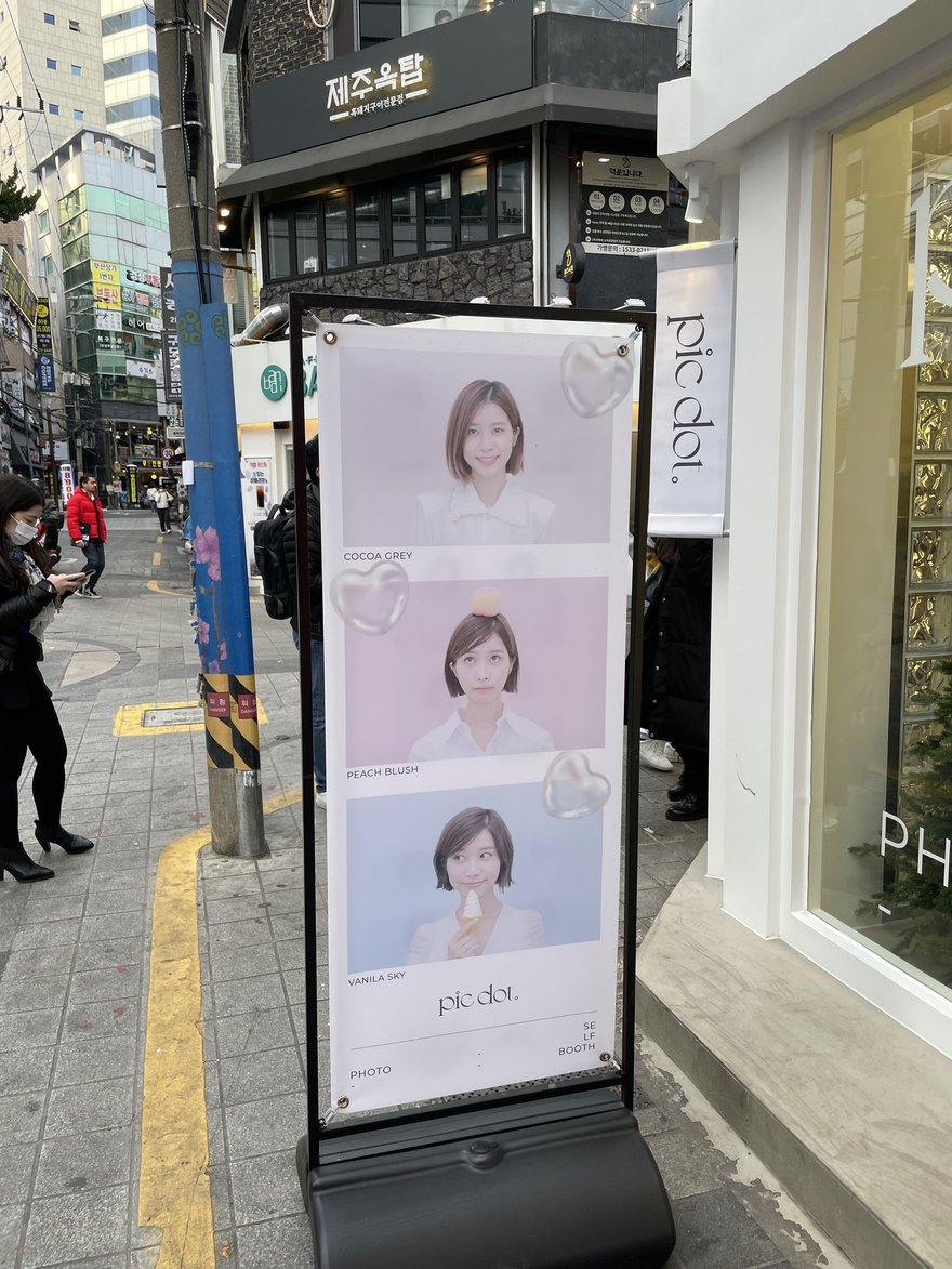 pic dot 店面外的立式燈箱看板，以三段直式版面呈現女性模特兒的自助拍照樣張，底部印 pic dot