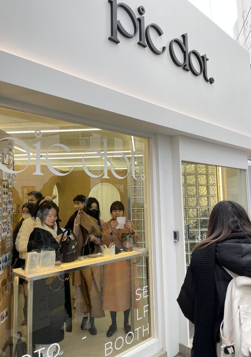 pic dot 店內的顧客，數名年輕客人在櫃檯區與樣張牆前等候
