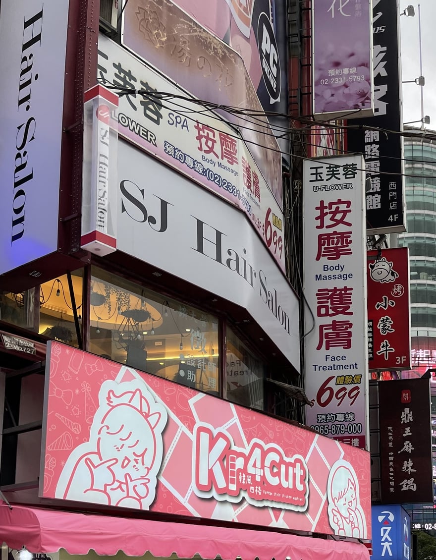 西門町成都路上的門市招牌，粉紅底寫 Kr4Cut 韓風四格，招牌位於 SJ Hair Salon 上方，周邊是西門町密集的商家看板