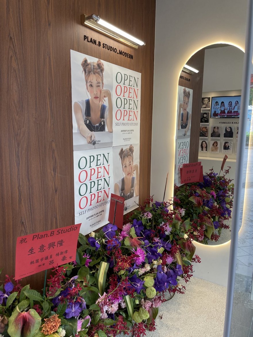 Plan.B Studio 西門店開幕當天的店內陳設，木牆掛 PLAN.B STUDIO_MODERN 棚名牌與四張 OPEN 海報，地上排滿開幕花籃，其中一張紅色賀卡具名桃園市議員楊朝偉