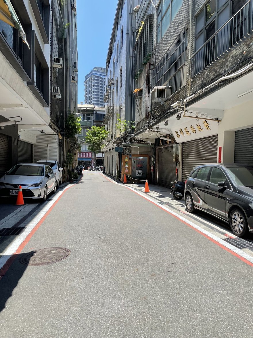 台北大同區太原路 11 巷的巷弄街景，兩側是拉下鐵捲門的服飾批發店與金字招牌，Error8 鼬鼠拍貼店的木作門面位在巷子中段