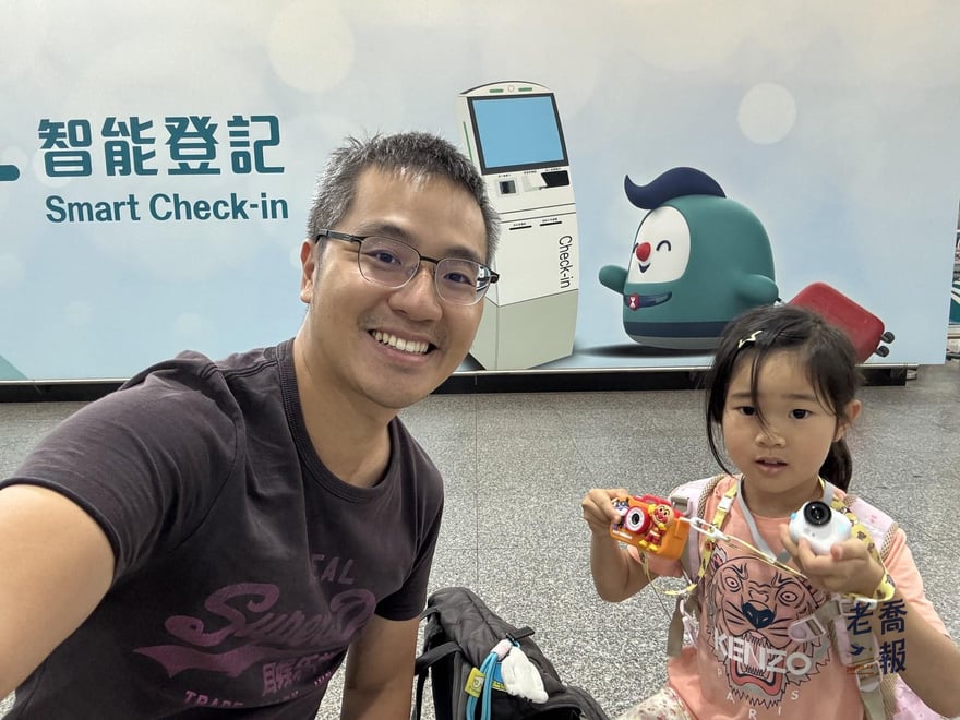 老喬與哈哈在香港站的智能登記 Smart Check-in 指引牆前自拍