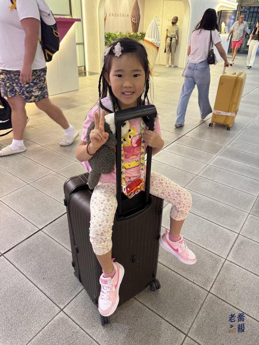哈哈坐在行李箱上，背景是桃園機場的出境大廳