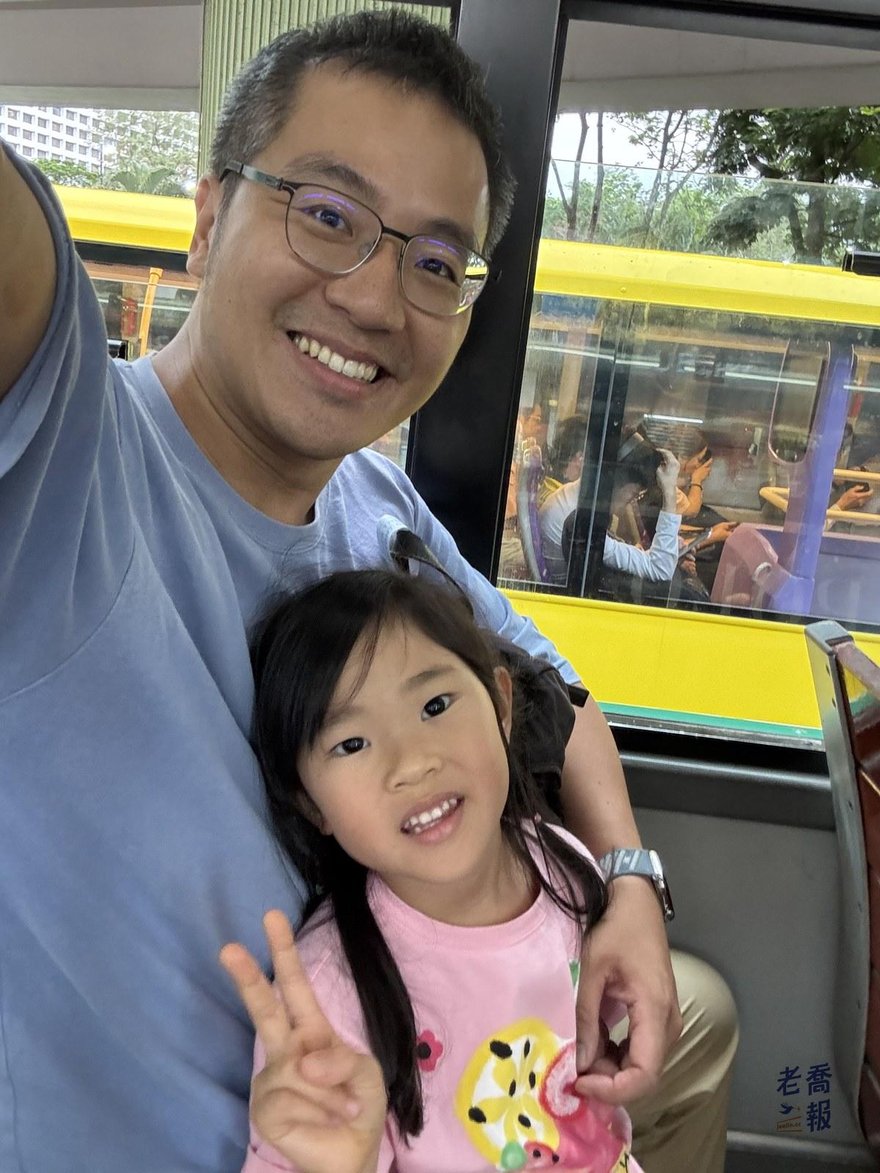 哈哈坐在叮叮車上，窗外是香港街景