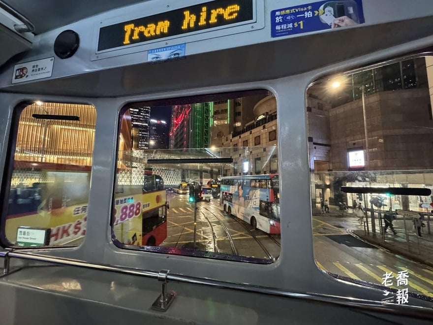 夜晚的叮叮車車頭，前方電子牌顯示班次資訊，街上是香港的霓虹招牌