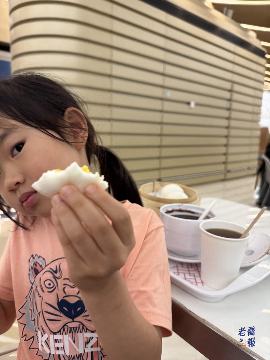 哈哈坐在機場餐廳裡拿著一顆包子吃