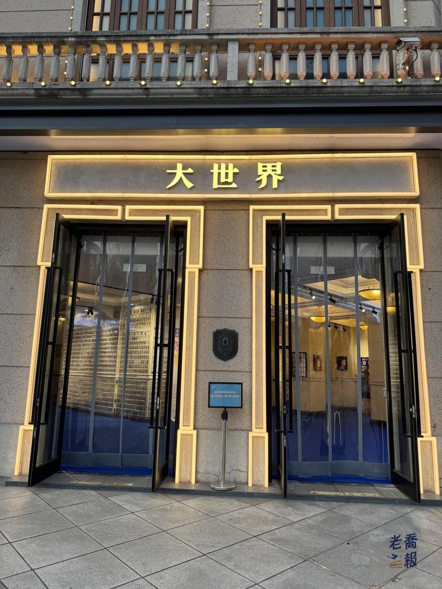 上海大世界一號門入口，米色石材門面上是金色的大世界三個字，兩扇玻璃門敞開，門內鋪著藍色地毯