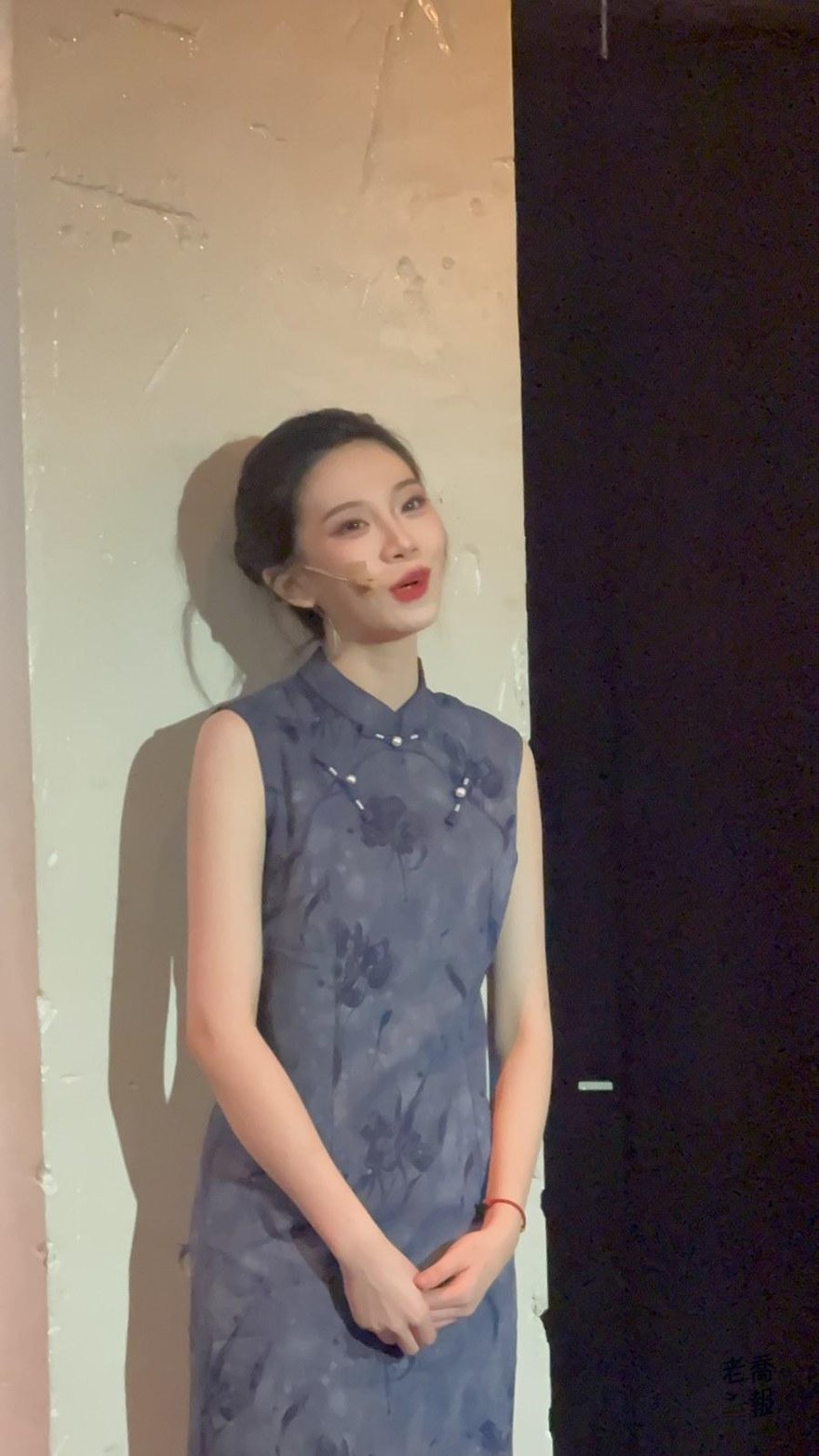 飾演小月的楊悅穿藍灰色印花旗袍站在米白色牆前獨唱，雙手交握在身前，臉頰上貼著麥克風