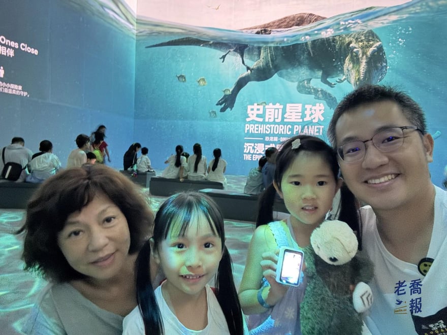 老喬與家人在史前星球展覽入口主視覺牆前的合照