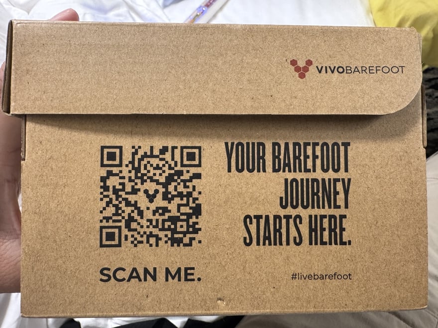 Vivobarefoot 鞋盒正面印著一個 QR 碼與 SCAN ME 字樣，旁邊寫著 YOUR BAREFOOT JOURNEY STARTS HERE 與標籤 hashtag livebarefoot。