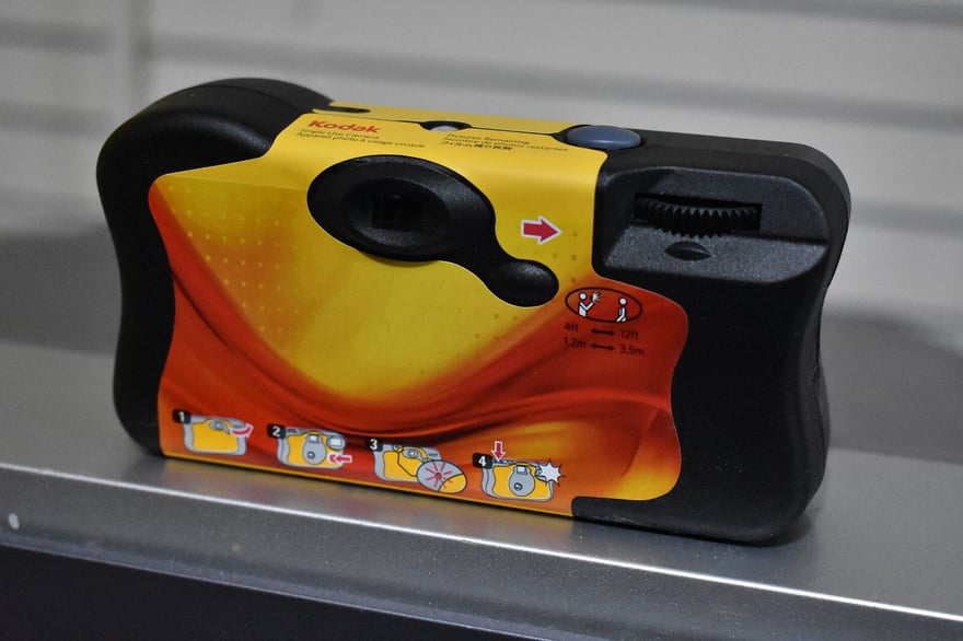 Kodak 附閃光燈的一次性相機背面，橘黃色紙套上印著四格操作圖示與閃光燈有效距離 1.2–3.5 公尺的標示，右上是捲片輪，2018 年拍攝。