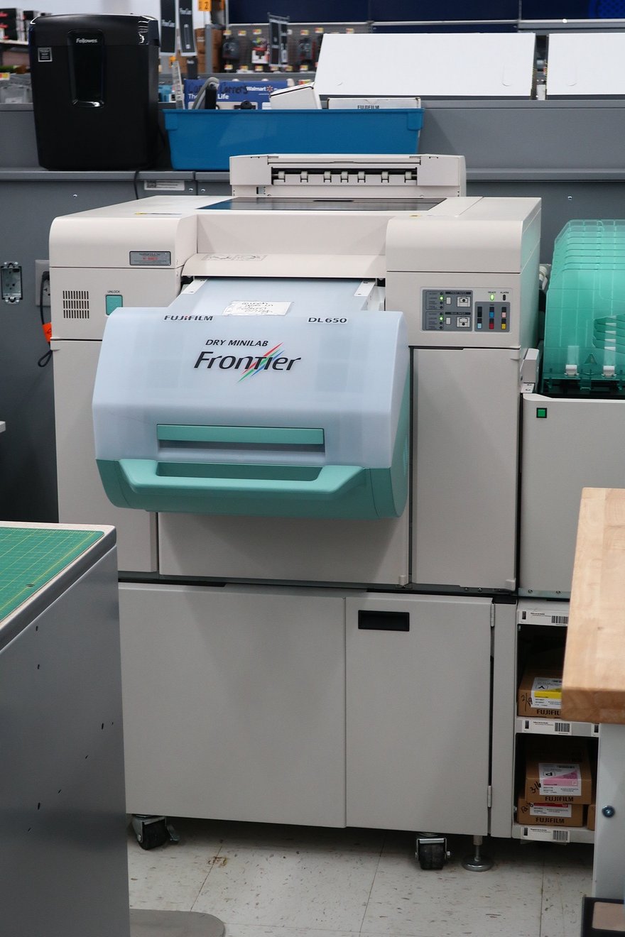 富士 FUJIFILM DRY MINILAB Frontier DL650 沖印機實機，機身下方堆放著富士原廠耗材紙盒