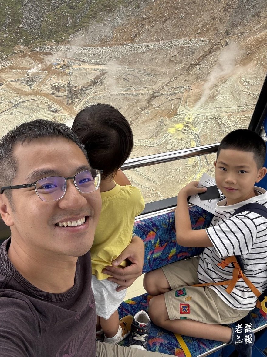從下山的纜車廂窗口俯瞰大涌谷砂防階地，規則的弧形擋土階一路排到蒸氣區邊緣，窗上貼著禁用手機的告示