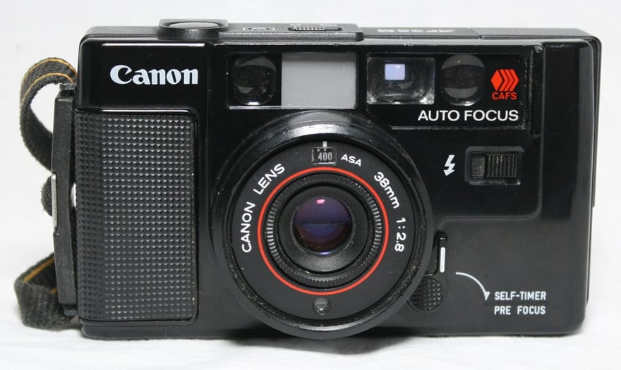 Canon AF35M की सामने से फ़ोटो: काली बॉडी, लेंस रिंग पर Canon Lens 38mm 1:2.8 लिखा है, लेंस के ऊपर छोटी खिड़कियों की कतार के पास AUTO FOCUS और CAFS के निशान, नीचे दाईं ओर सेल्फ़-टाइमर और फ़ोकस-लॉक का लीवर।