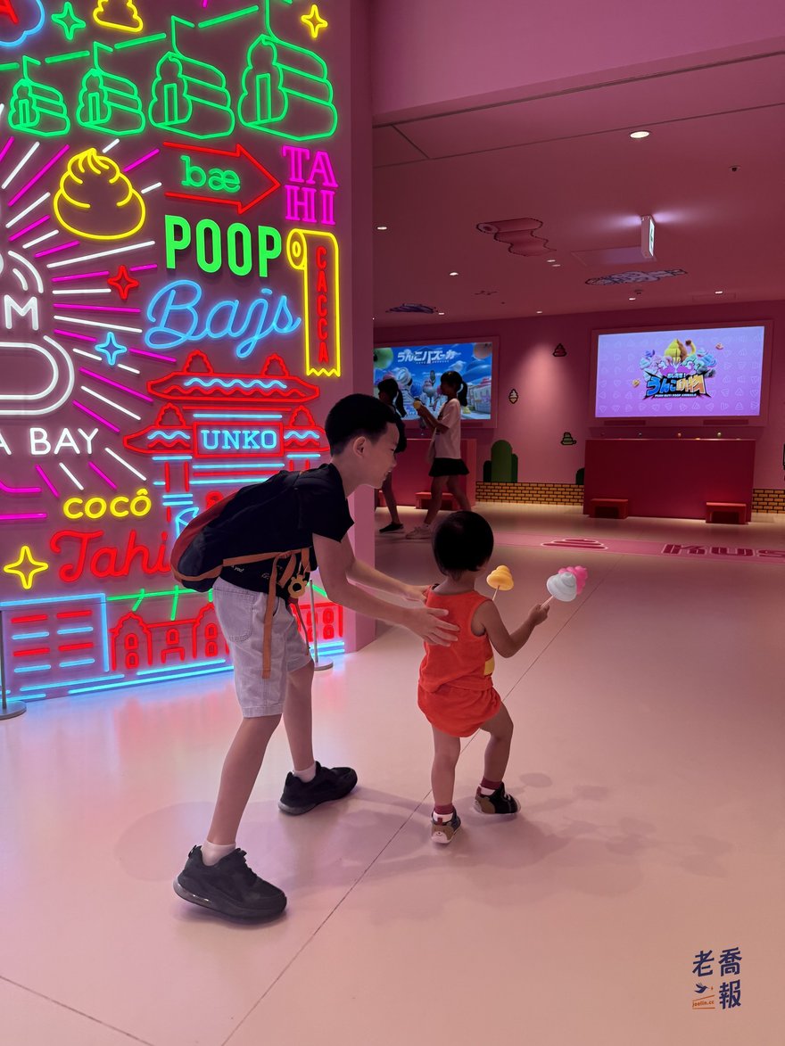 哥哥牽著拿彩色便便的圈圈，在展場裡一起跳躍著去玩