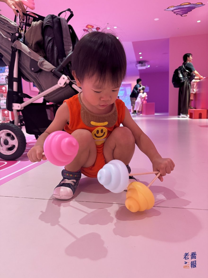 圈圈蹲在粉紅色展場地板上，把不同顏色的便便放在身邊
