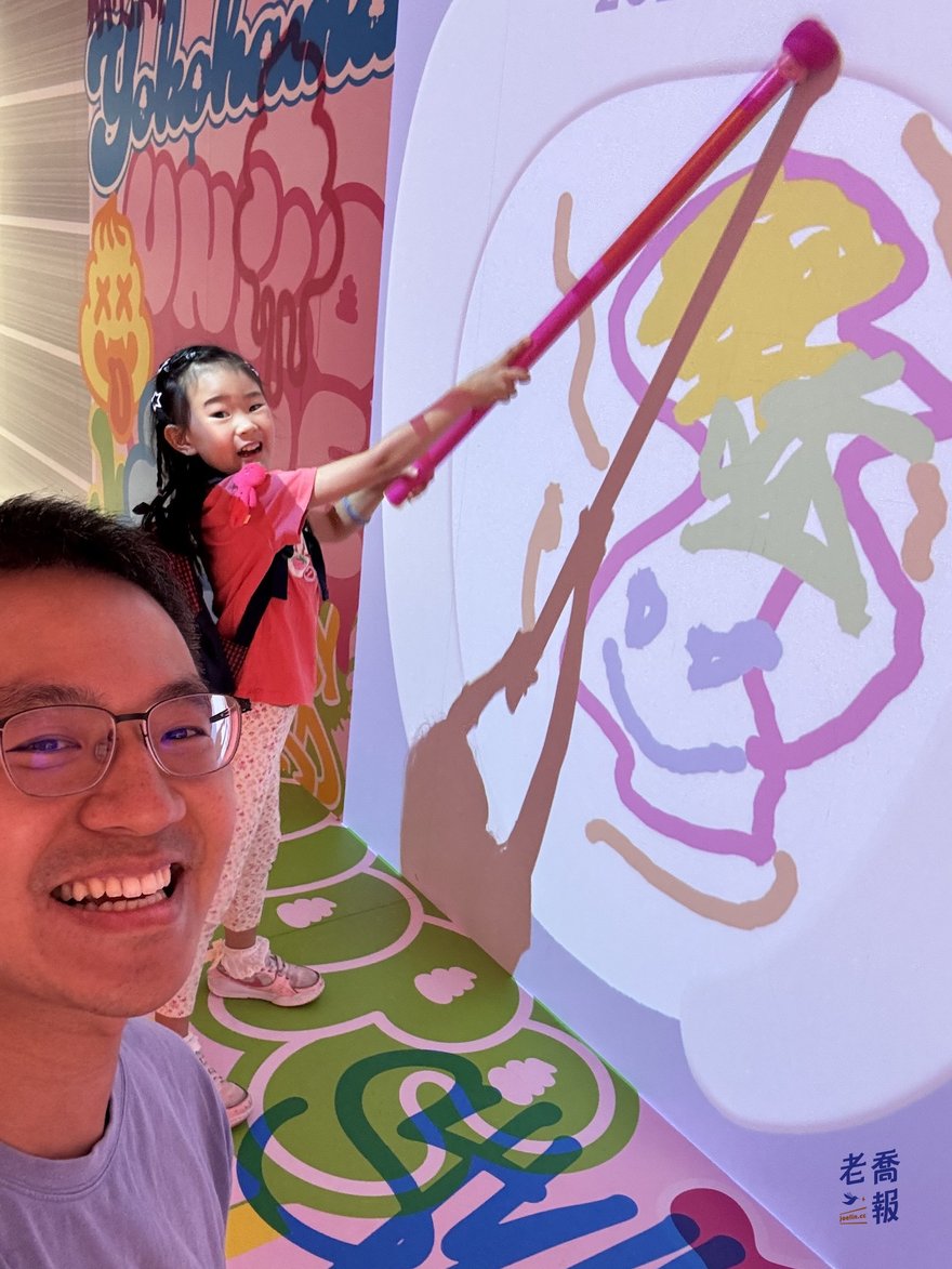 孩子在牆面投影前用長筆畫出自己的便便圖案