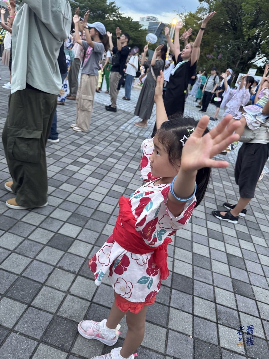 哈哈站在圓圈外圈，雙手高舉跟著大人做動作
