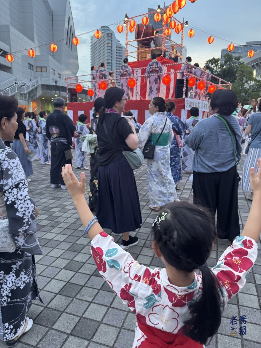 哈哈舉起雙手跟著跳，前方是繞著櫓走的浴衣人群