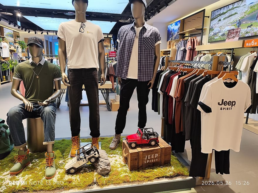 深圳福田購物中心裡的 JEEP SPIRIT 服飾店櫥窗：三個穿著休閒襯衫與卡其褲的假人，站在草地造景上，旁邊擺著越野車模型，右邊衣架掛著印有 Jeep 字樣的 T 恤。